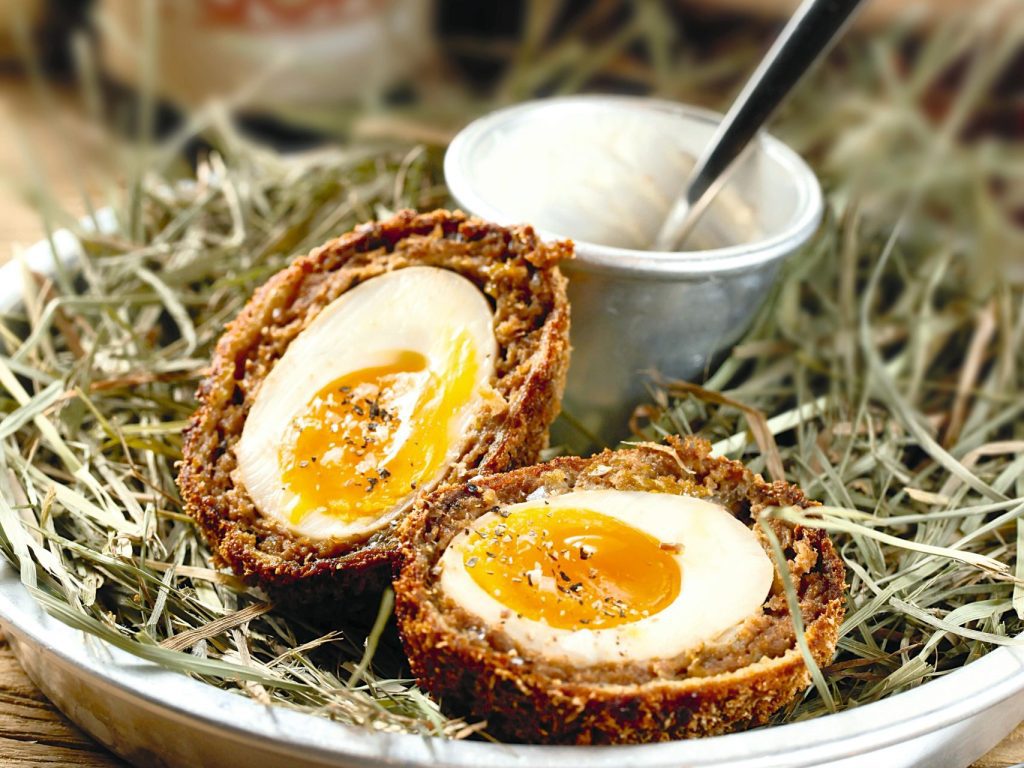 pexels photo 7491951 7491951 A gourmet scotch egg served in a rustic style with a side of sauce, perfect for culinary presentations.